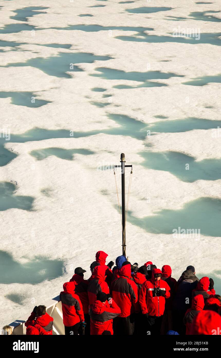 Arctic expedition passengers wearing red sailing through ice. Stock Photo