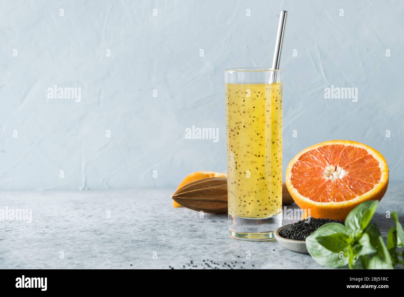 Basil seeds drink with orange juice in glass on light background
