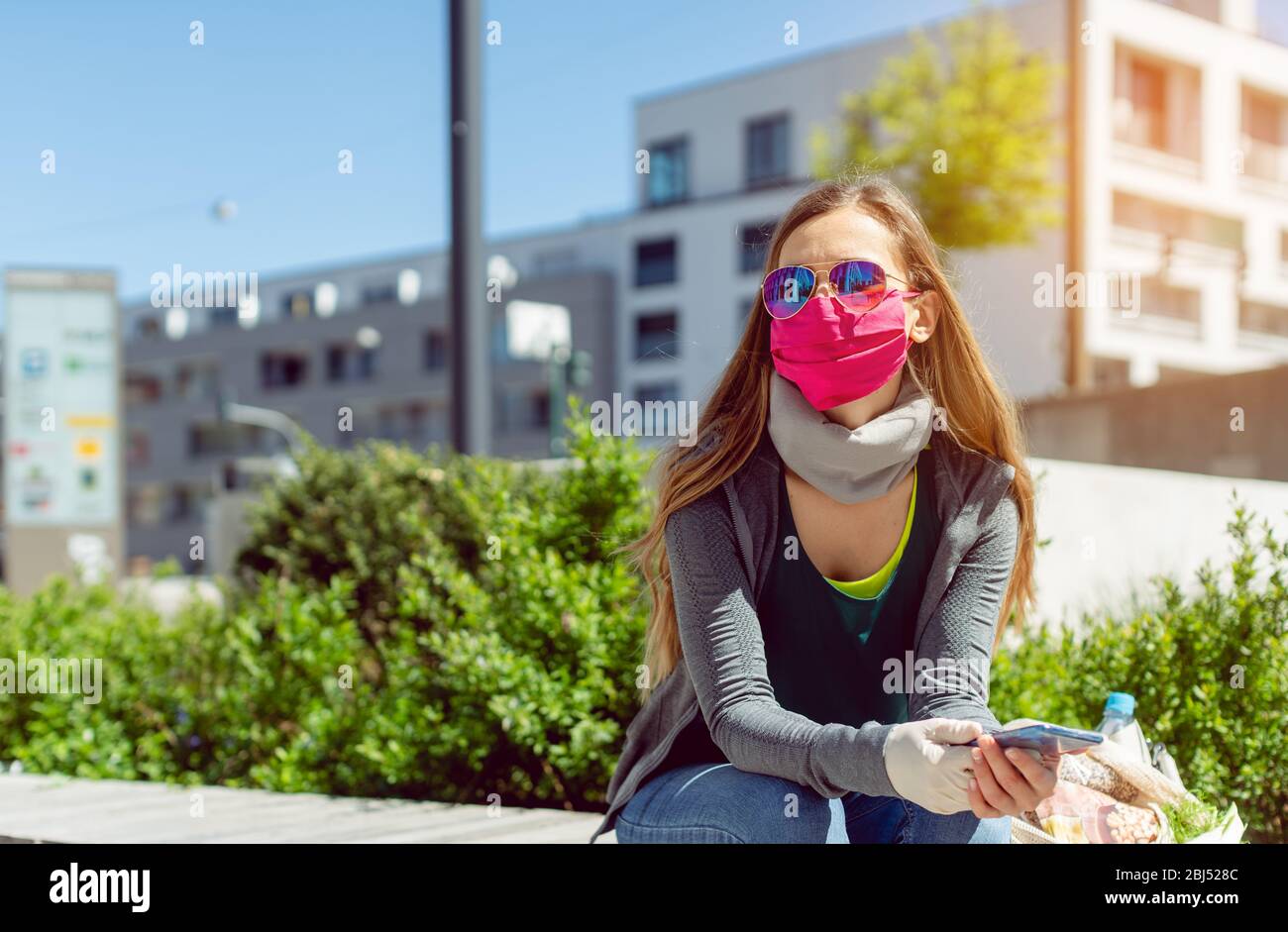 Woman with face mask sitting outside as lockdown opens Stock Photo