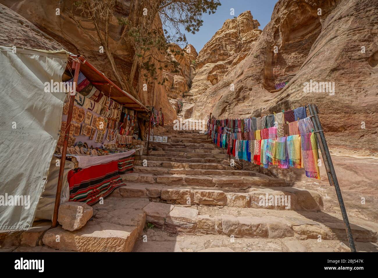 Passageways cut through the mountainous canyons of Petra in Jordan are lined with stands selling beautiful Bedouin crafts. Stock Photo