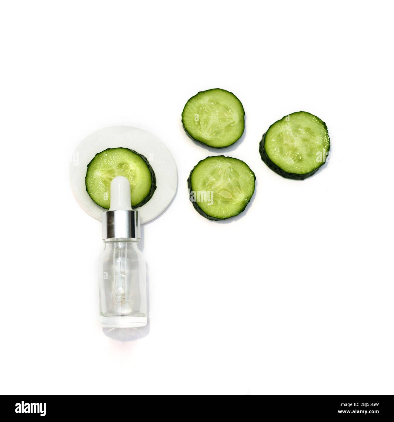 A cosmetic bottle and many sliced cucumbers on the white background. Natural cosmetics. Stock Photo