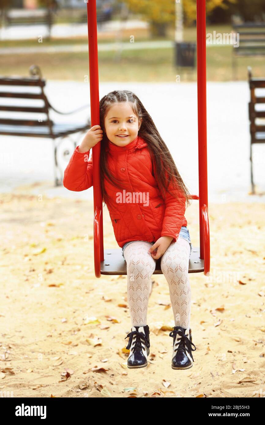 Little girl on swing in city park Stock Photo