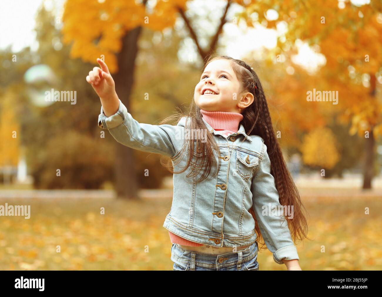 Cute girl playing with soap bubbles in park Stock Photo - Alamy