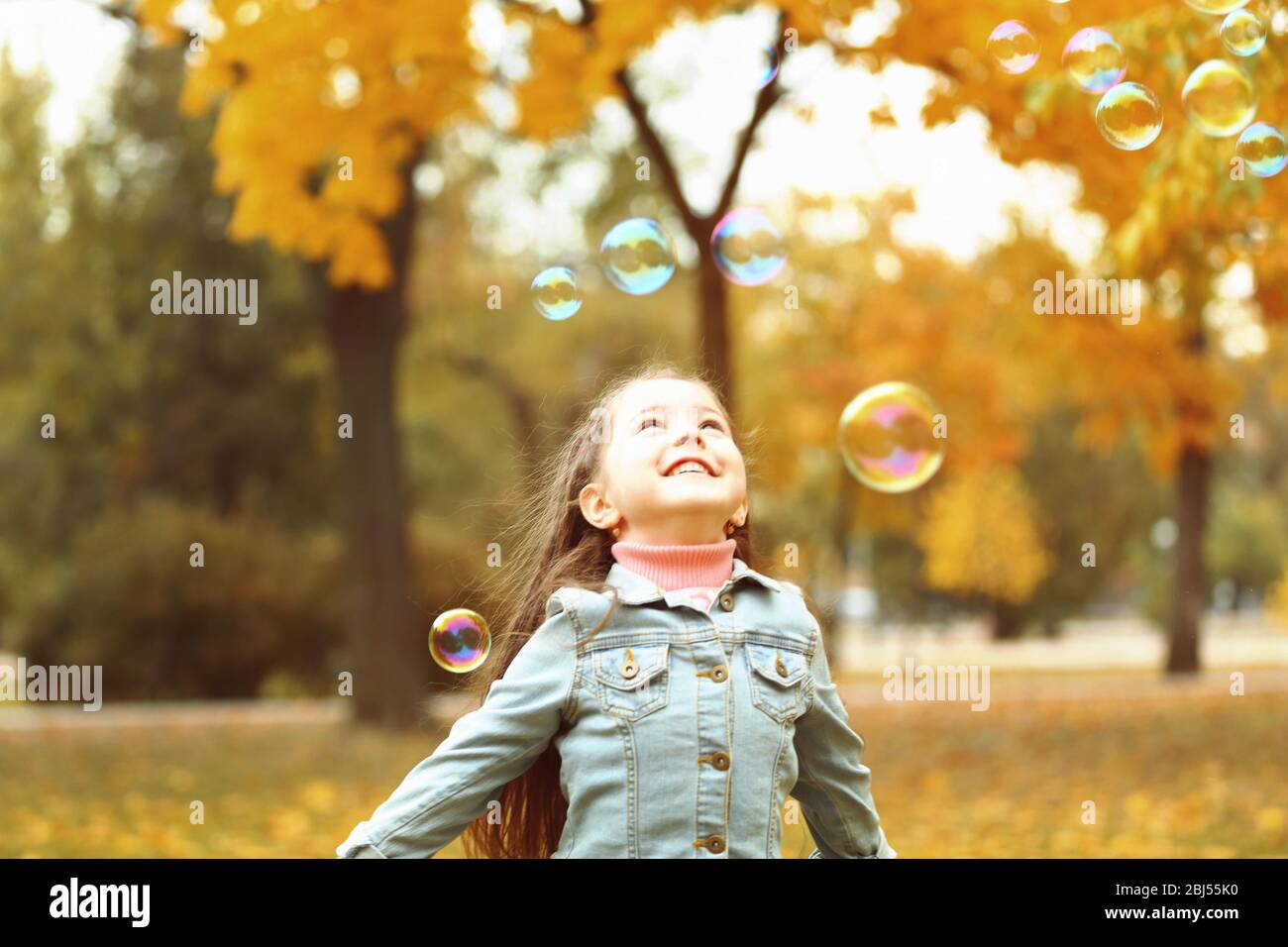 Cute girl playing with soap bubbles in park Stock Photo - Alamy