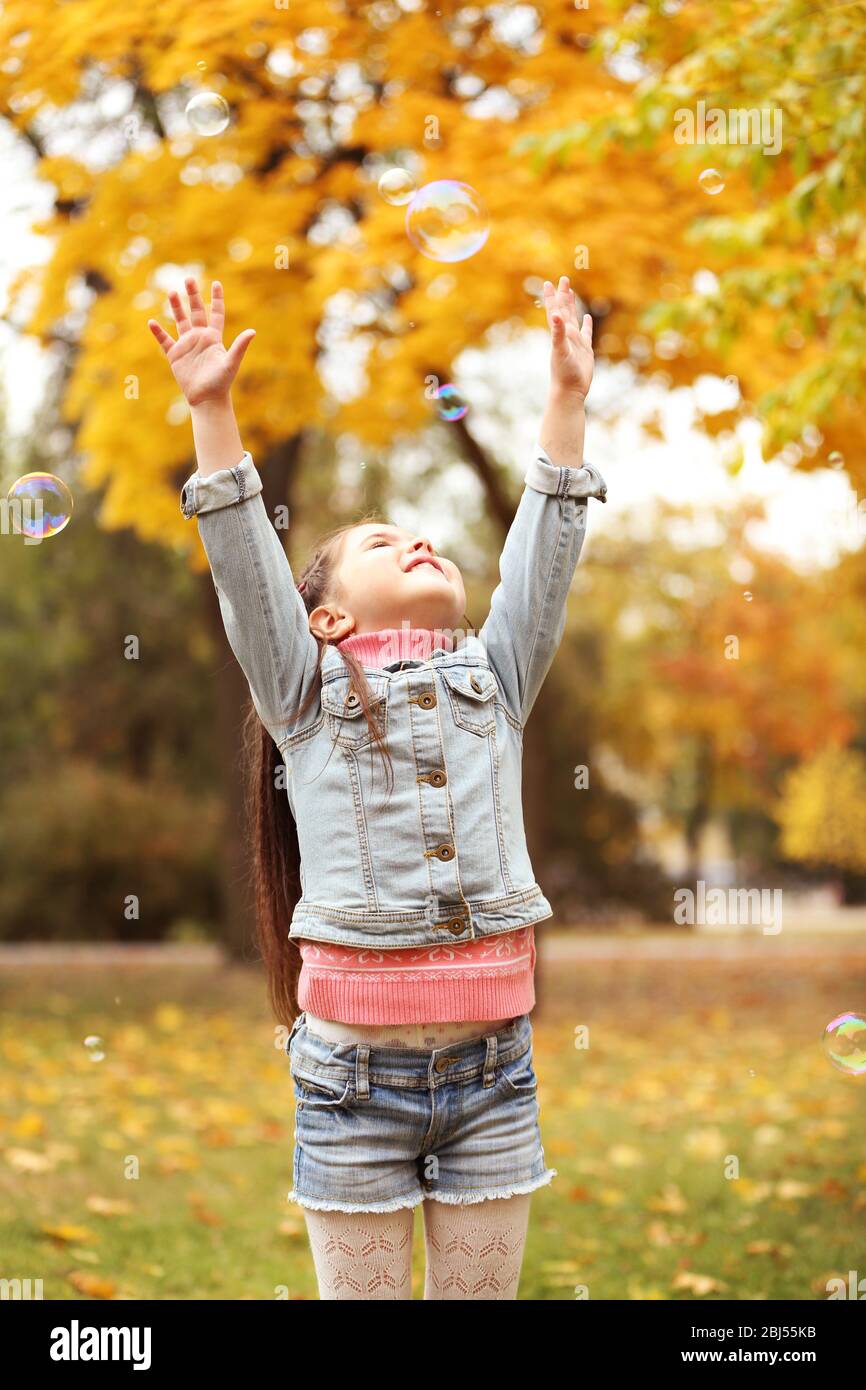 Cute girl playing with soap bubbles in park Stock Photo - Alamy