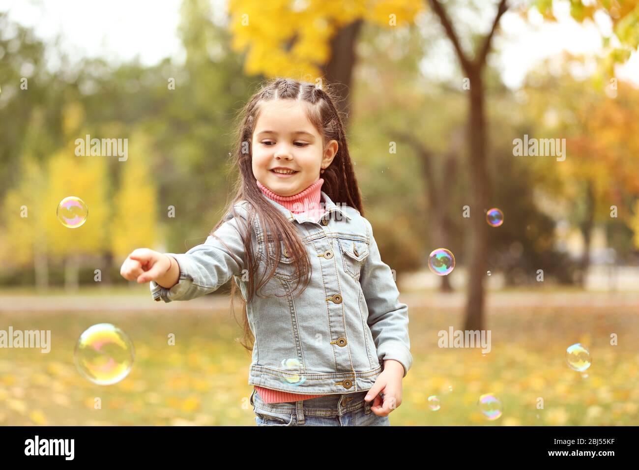 Cute girl playing with soap bubbles in park Stock Photo - Alamy