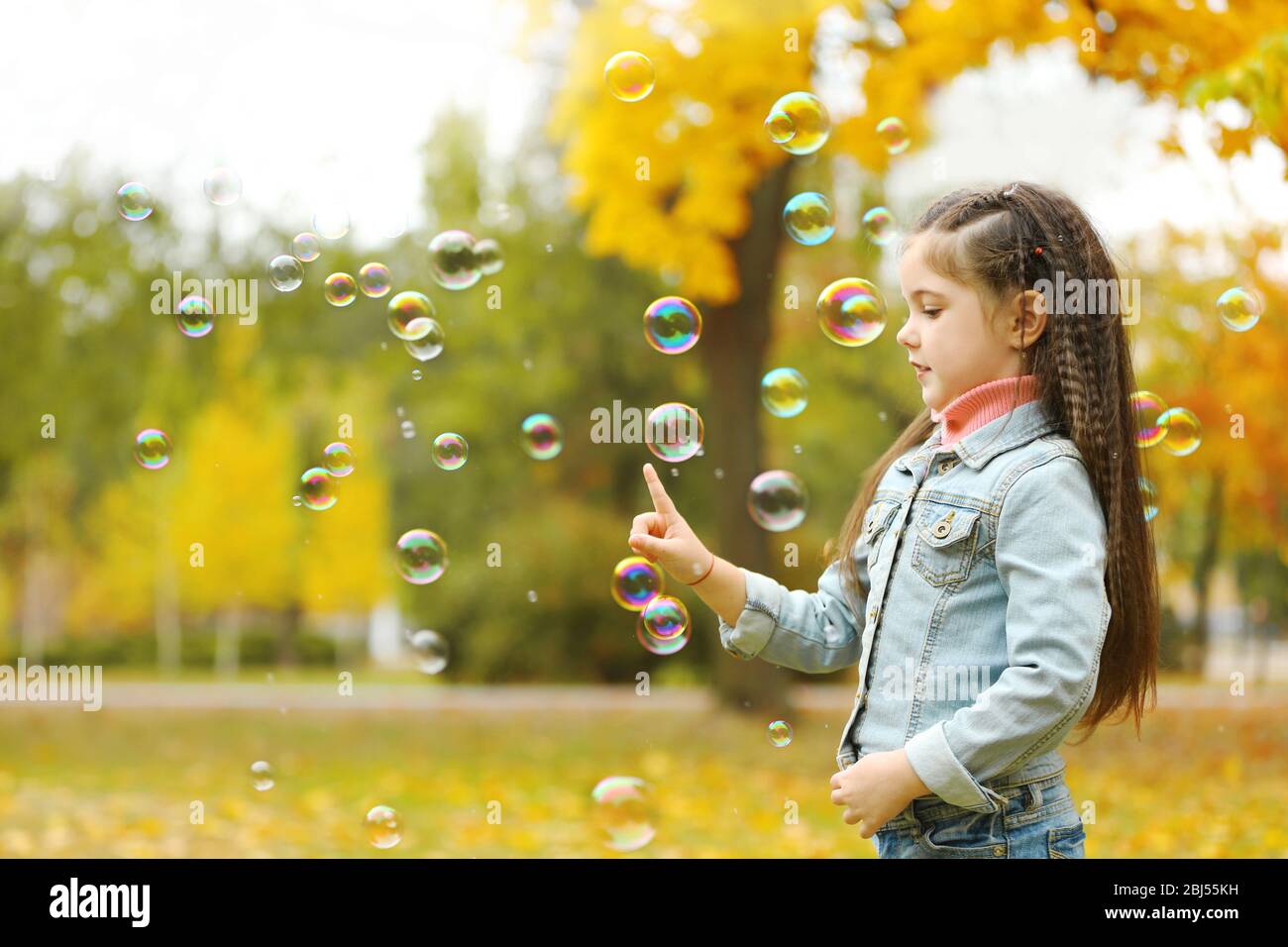 Cute girl playing with soap bubbles in park Stock Photo - Alamy