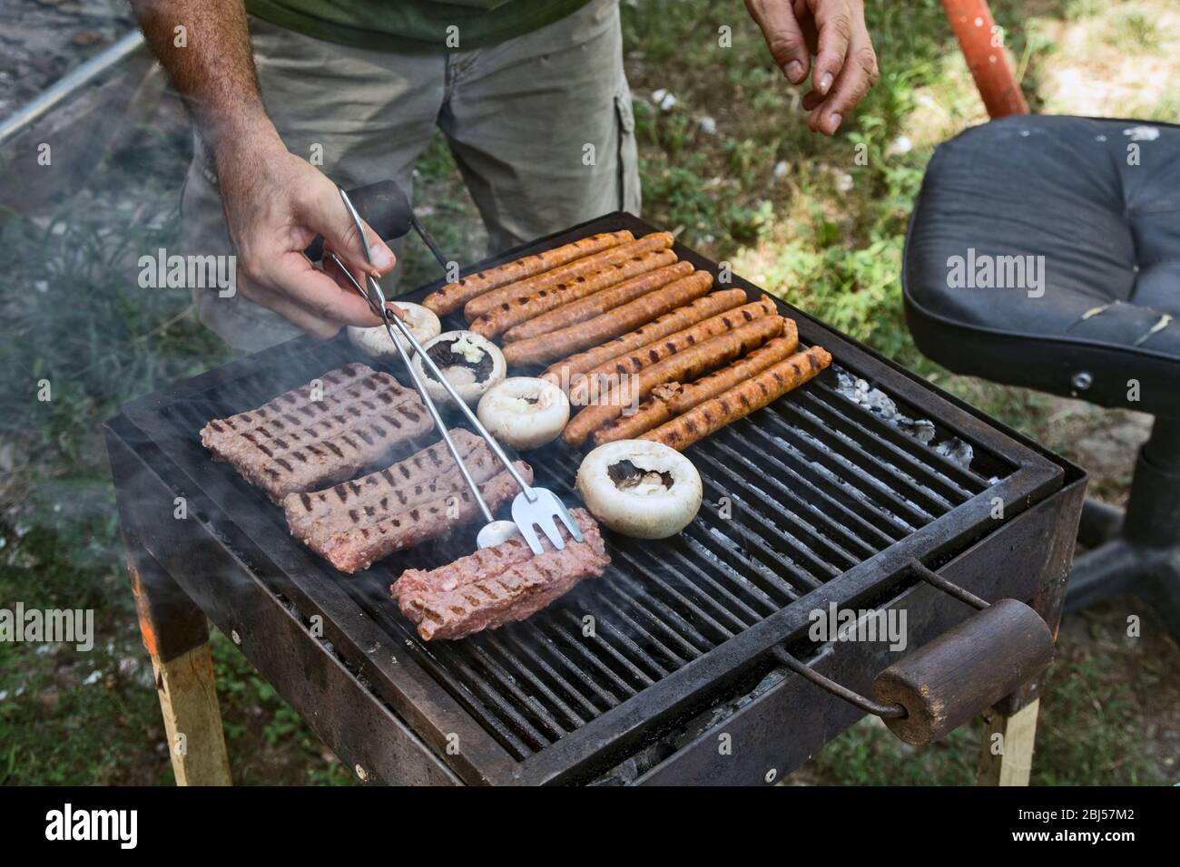 Preparing barbecue meat at picnic in nature. The meat is roasted in a  conventional way Stock Photo - Alamy