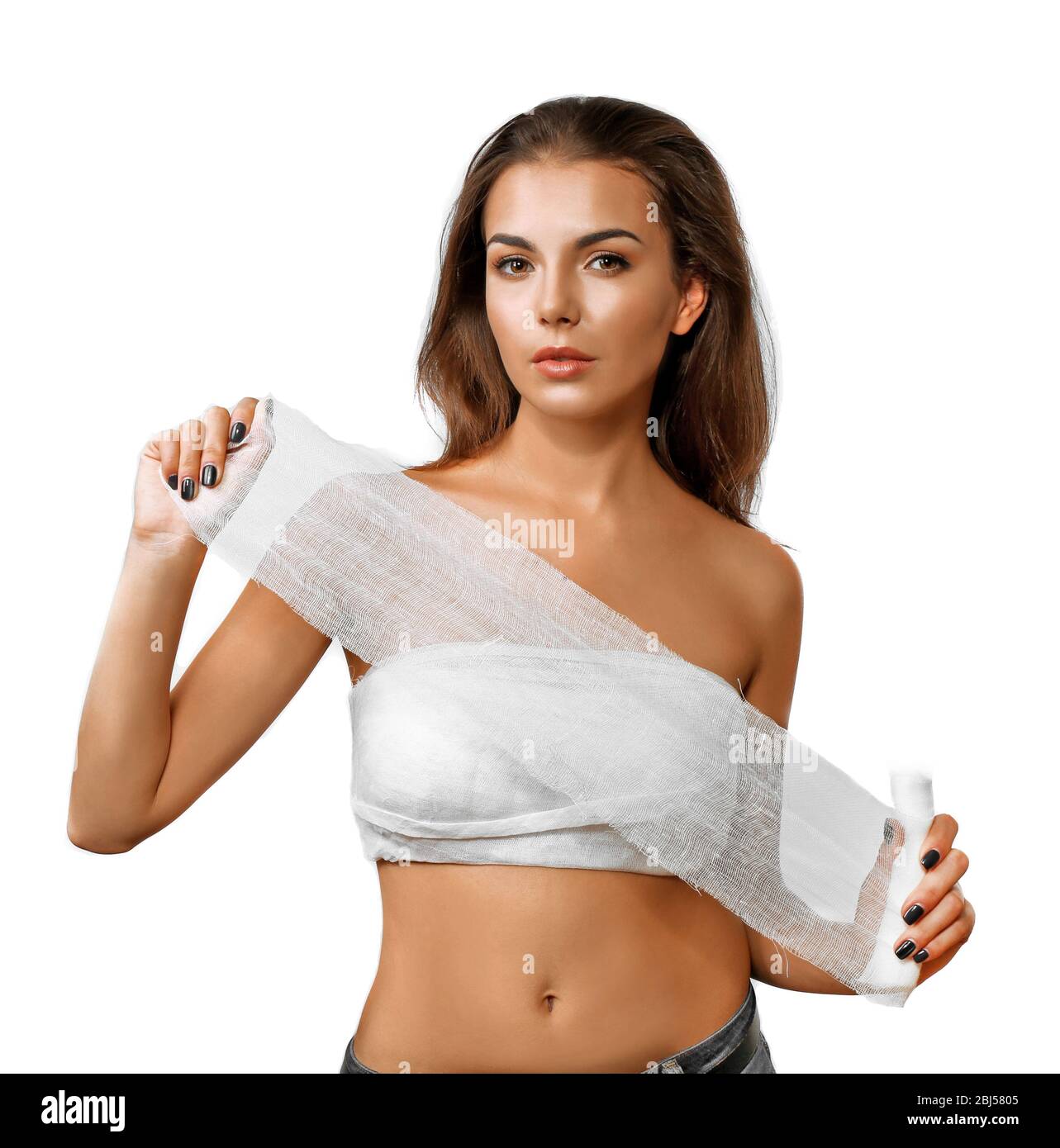 Doctor wrapping bandage around young woman's chest on grey background,  closeup Stock Photo