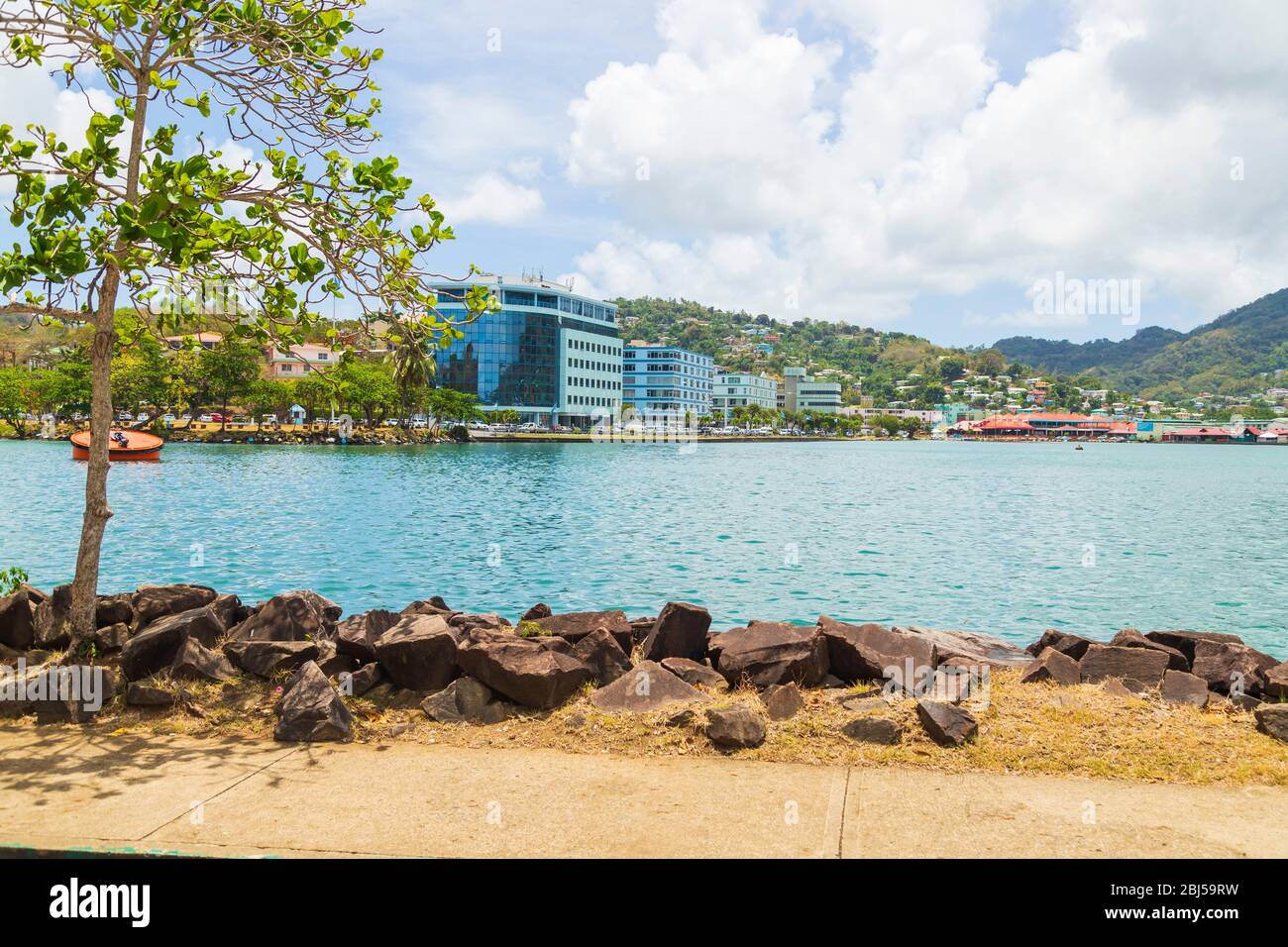 Castries, Saint Lucia - April 15 2020: the water of the Castries harbor between rocks on the near side and hills and buildings in the background Stock Photo
