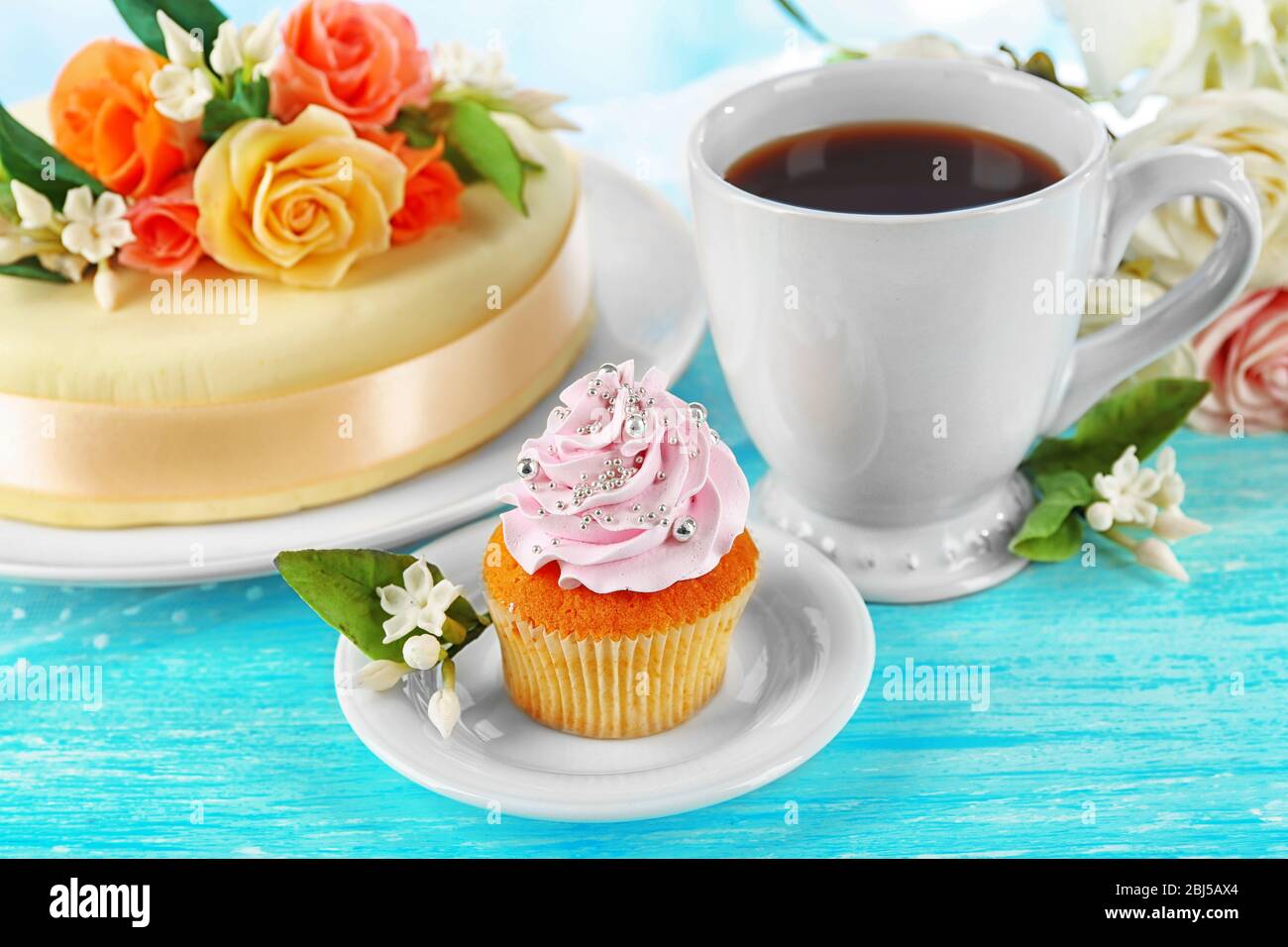 Cake with sugar paste flowers and cupcake, on light background Stock Photo