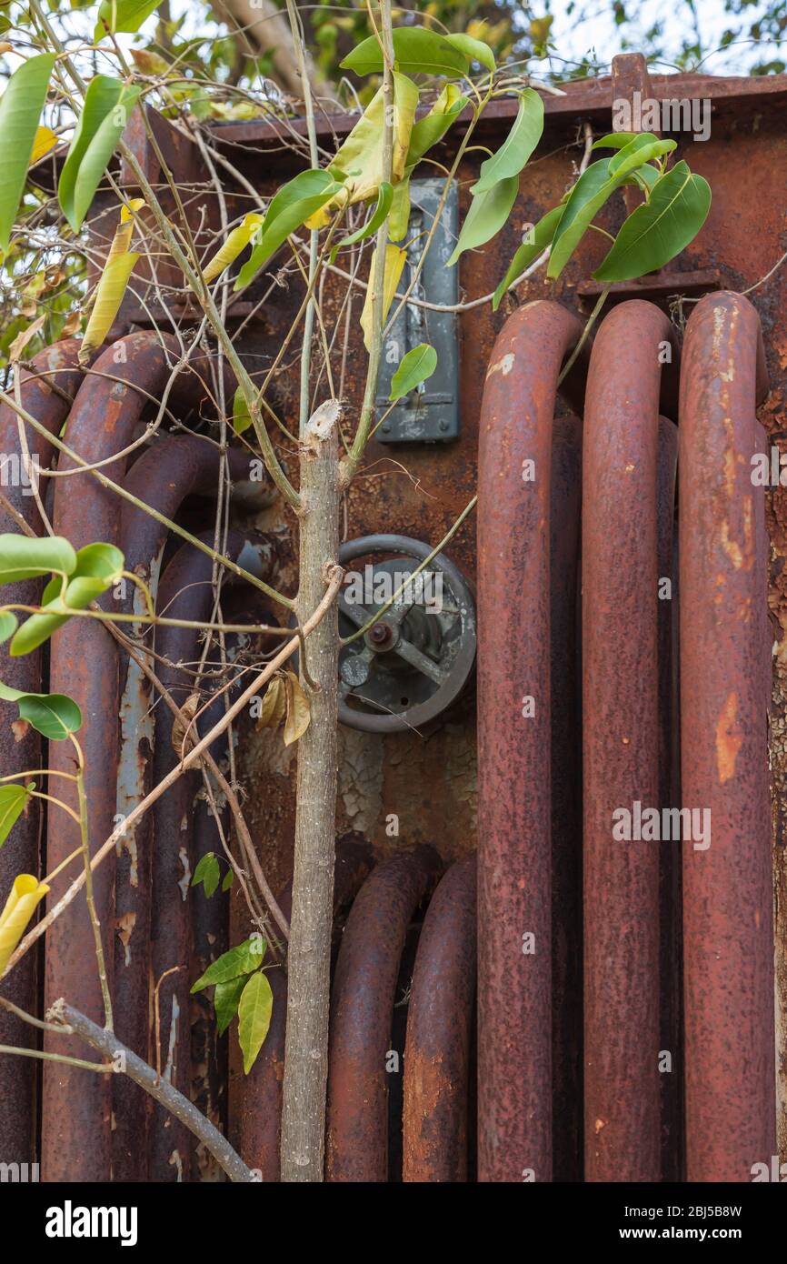 the front of an old 11000 volt rusted transformer with rusted pipes and a hand wheel Stock Photo