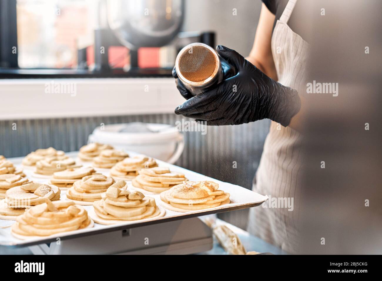 Small Business. Woman at bakery shop adding cinnamon on cakes close-up Stock Photo