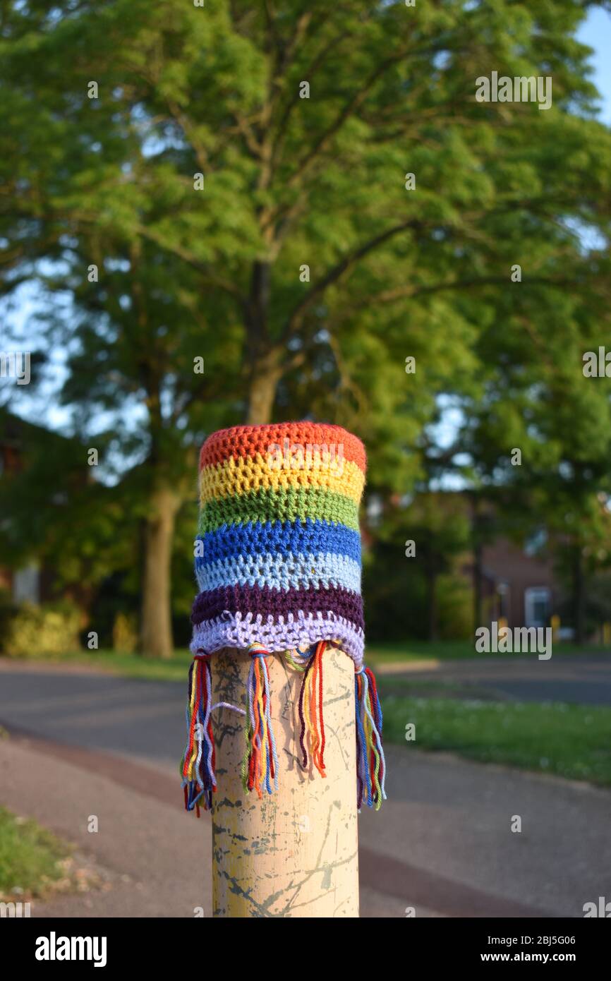 Guerilla knitting - a knitted Rainbow of Hope on a bollard in Milton Keynes, supporting the NHS during Covid-19. Stock Photo