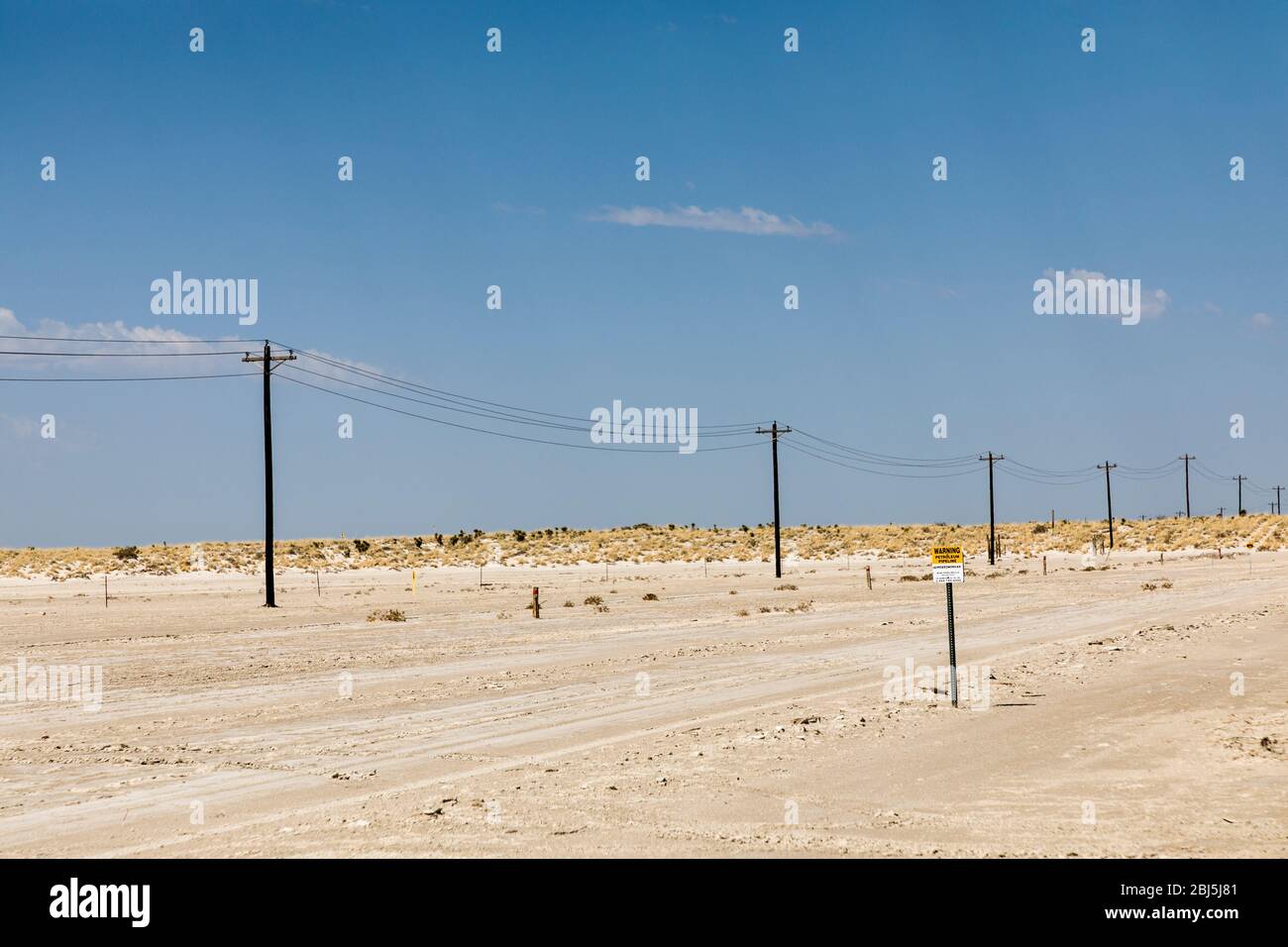 Telegraph line across desert regionwith warning sign for buried cable, New Mexico, USA Stock Photo