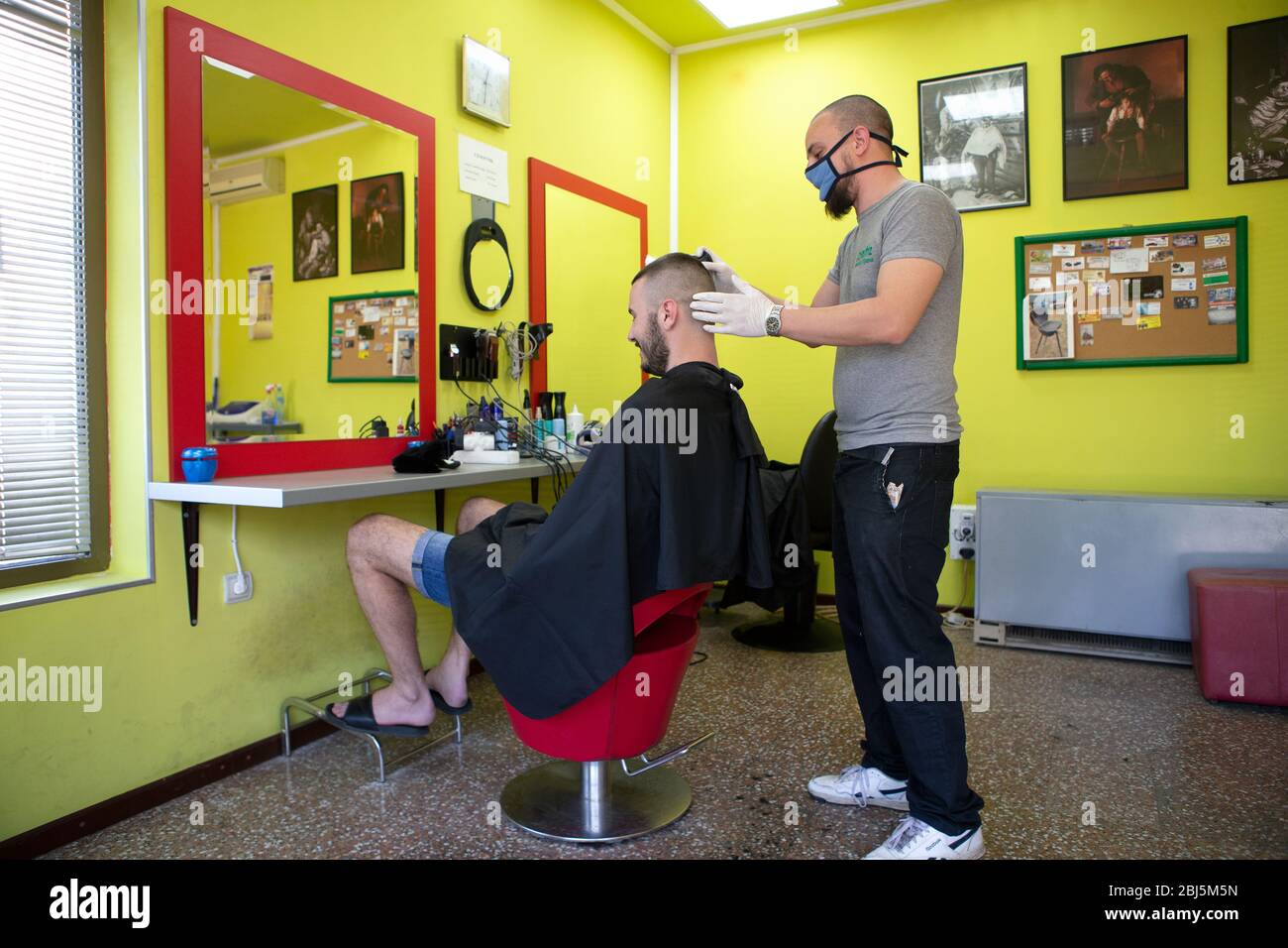Belgrade, Serbia. 28th Apr, 2020. The hairdresser with protective mask and gloves cuts the client's hair after the reopening during the coronavirus disease (COVID-19).  Serbian President Aleksandar Vucic had declared the state of emergency to stop the spread of the coronavirus. Following the drop in the number of coronavirus patients the government from this week allows the reopening of hairdressers, gyms and markets. Credit: Nikola Krstic/Alamy Live News Stock Photo