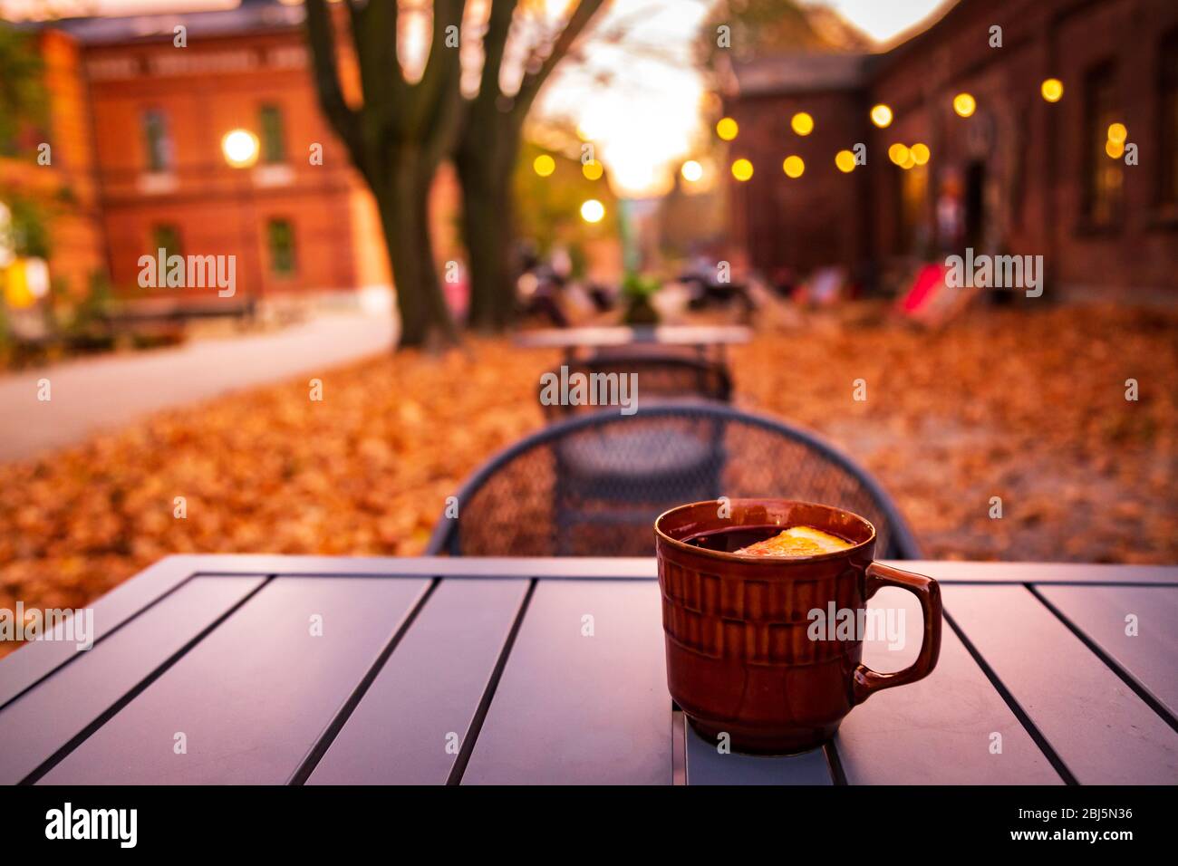 Lodz, Poland: A cup of hot drink on the table in the Ksiezy Mlyn historic distric during autumn evening Stock Photo