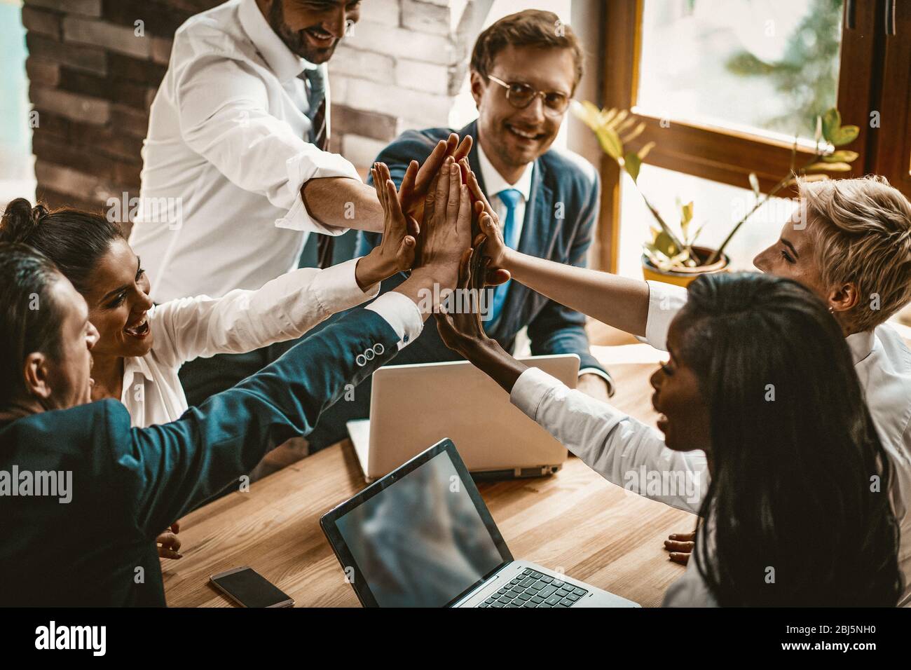 Happy Colleagues Joining Their Hands In High Five Gesture Stock Photo