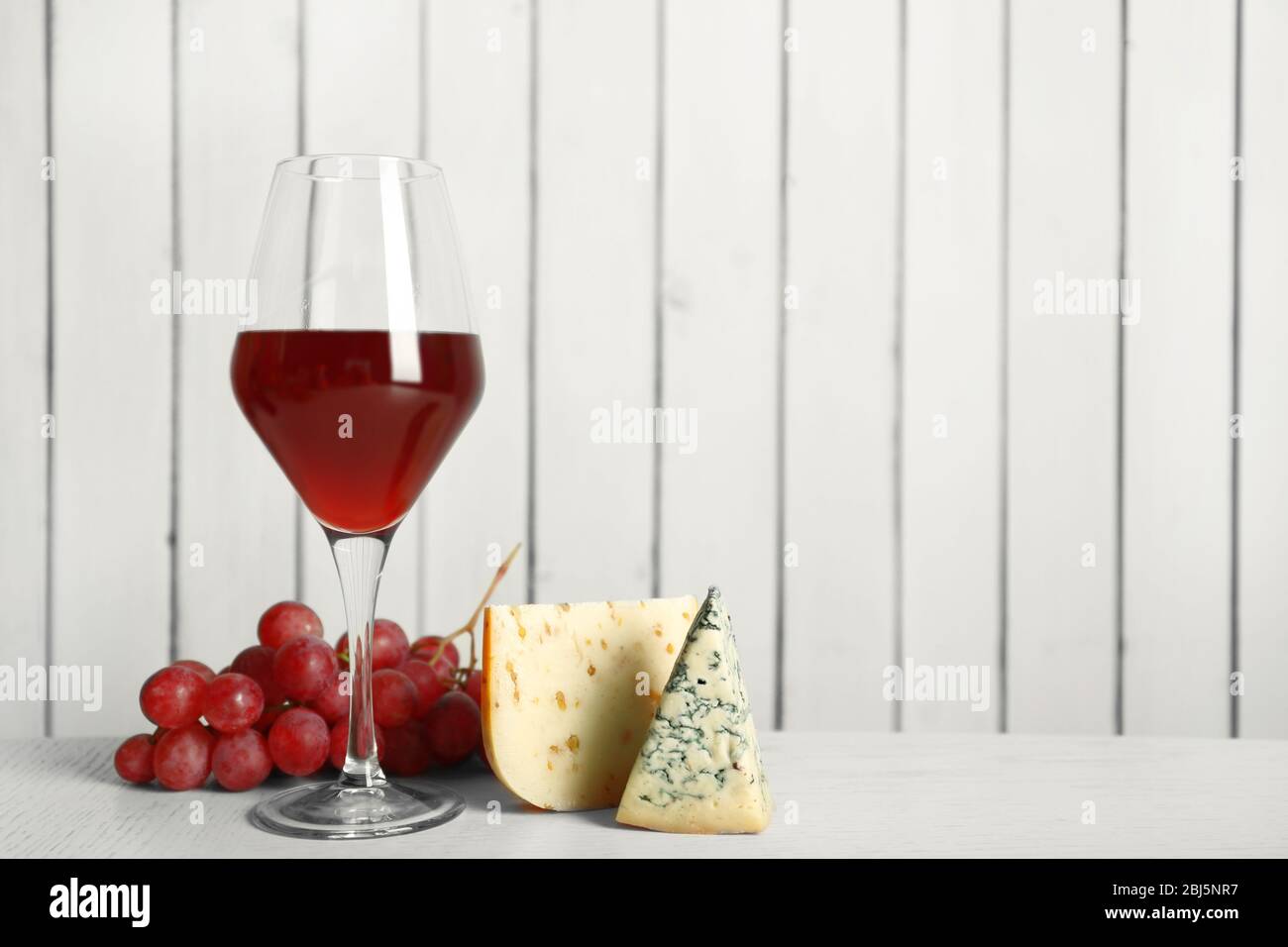 Red wine with cheese and grape on wooden wall background Stock Photo ...