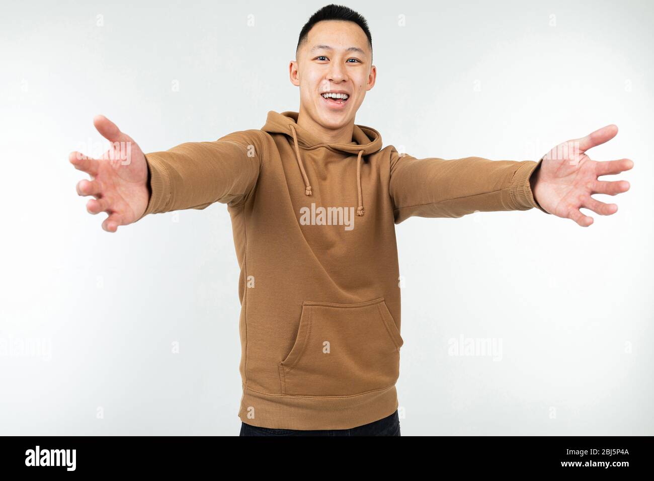 Asian man in brown hoodie with open arms on a white background Stock ...