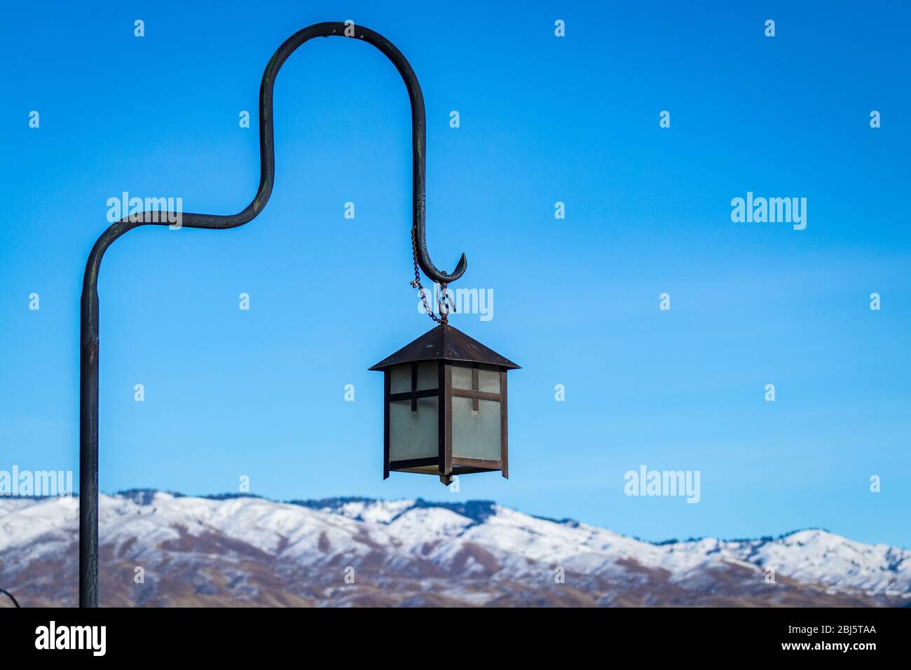 Hanging lamp stands against snow covered mountain and blue skies in scenic winter setting. Stock Photo