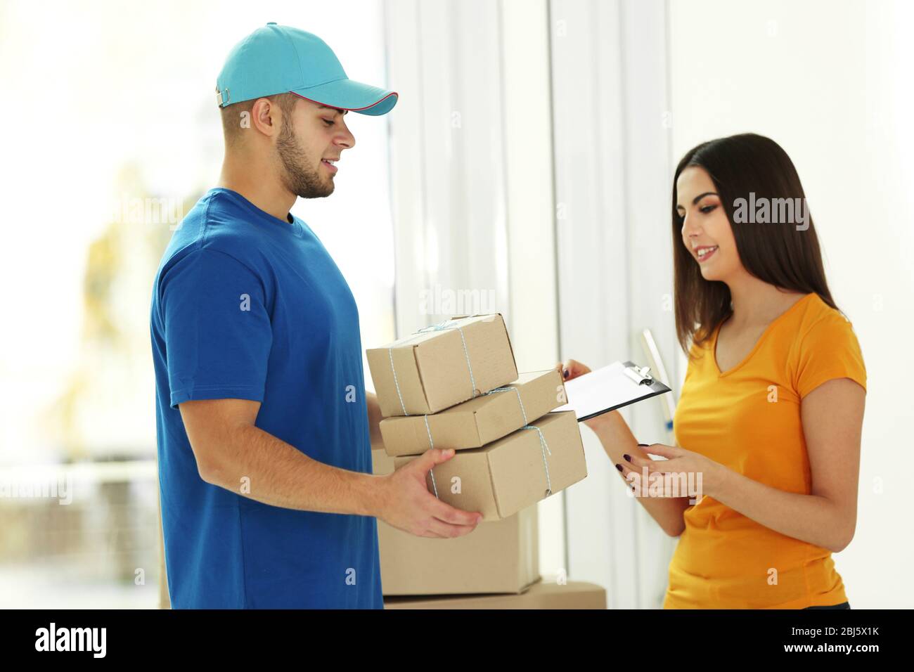 Receiving parcel delivery man gives package to young woman Stock