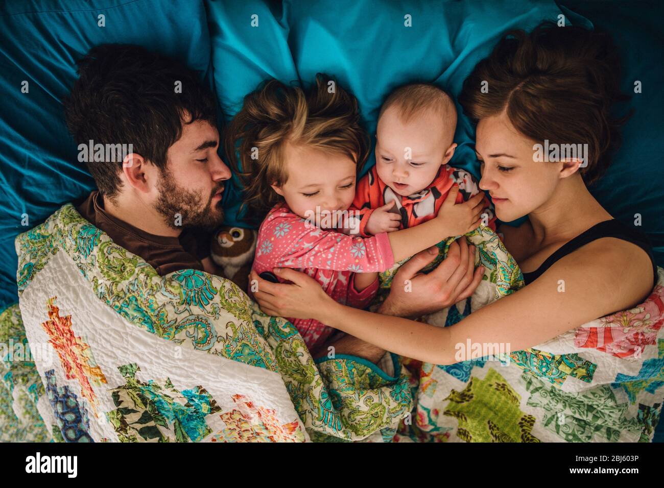 Mom and dad and children sleeping and hugging in bed in the morning Stock Photo