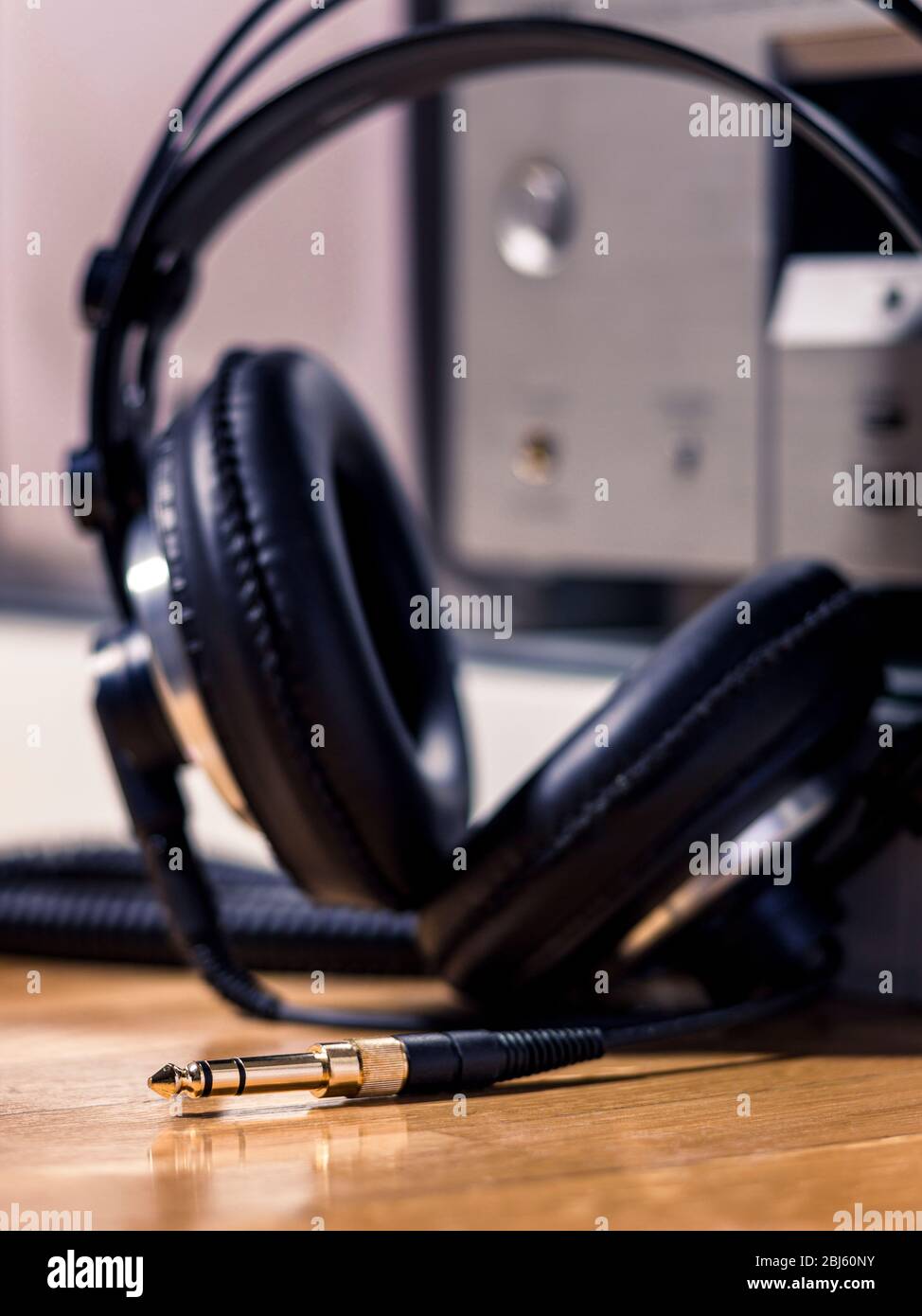 Black Hi-Fi headphones with a gold input jack on a wooden floor Stock Photo
