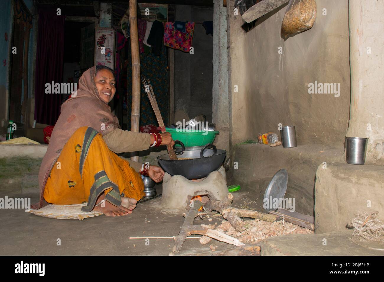 Rural Indian Woman cooking food in the Kitchen using firewood stove Stock Photo