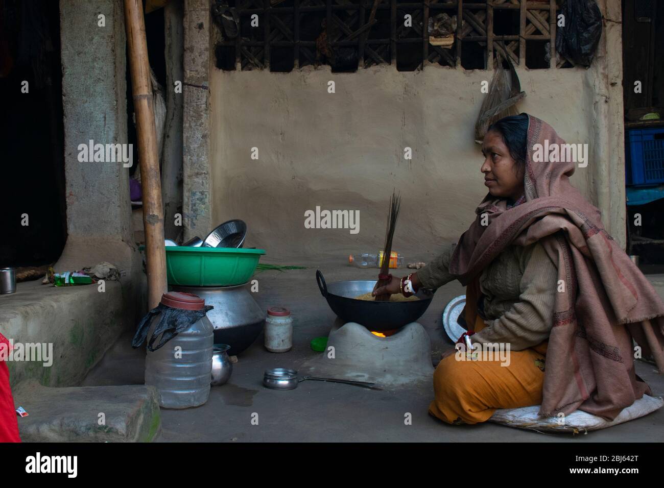 Rural Indian Woman cooking food in the Kitchen using firewood stove Stock Photo