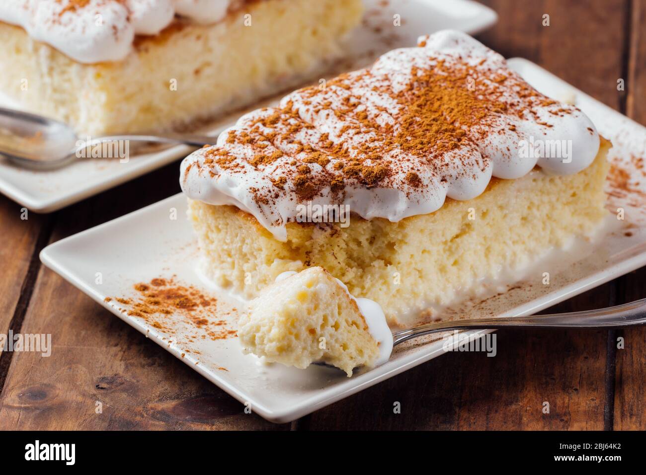 Two pieces of a delicious three milk cake dessert on a wooden background Stock Photo