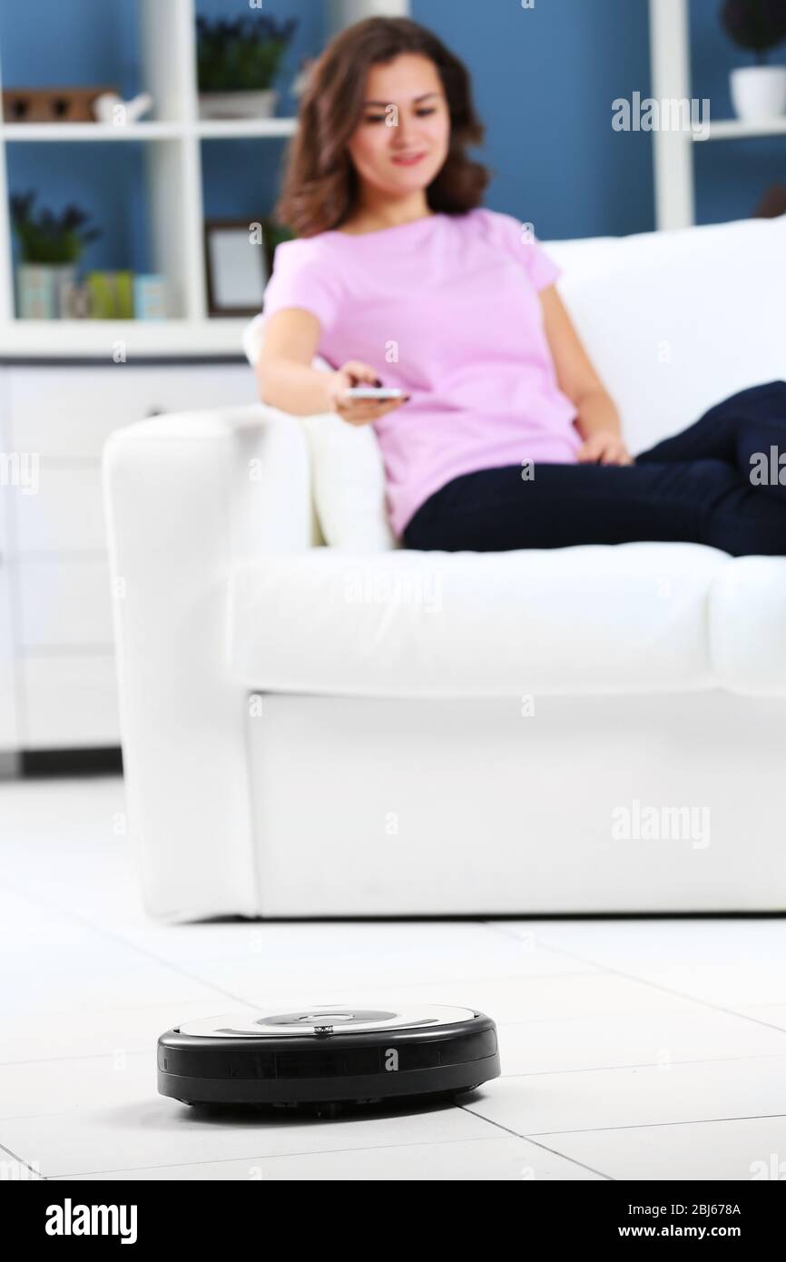 Cleaning concept - automatic robotic hoover clean the room while woman relaxing, close up Stock Photo