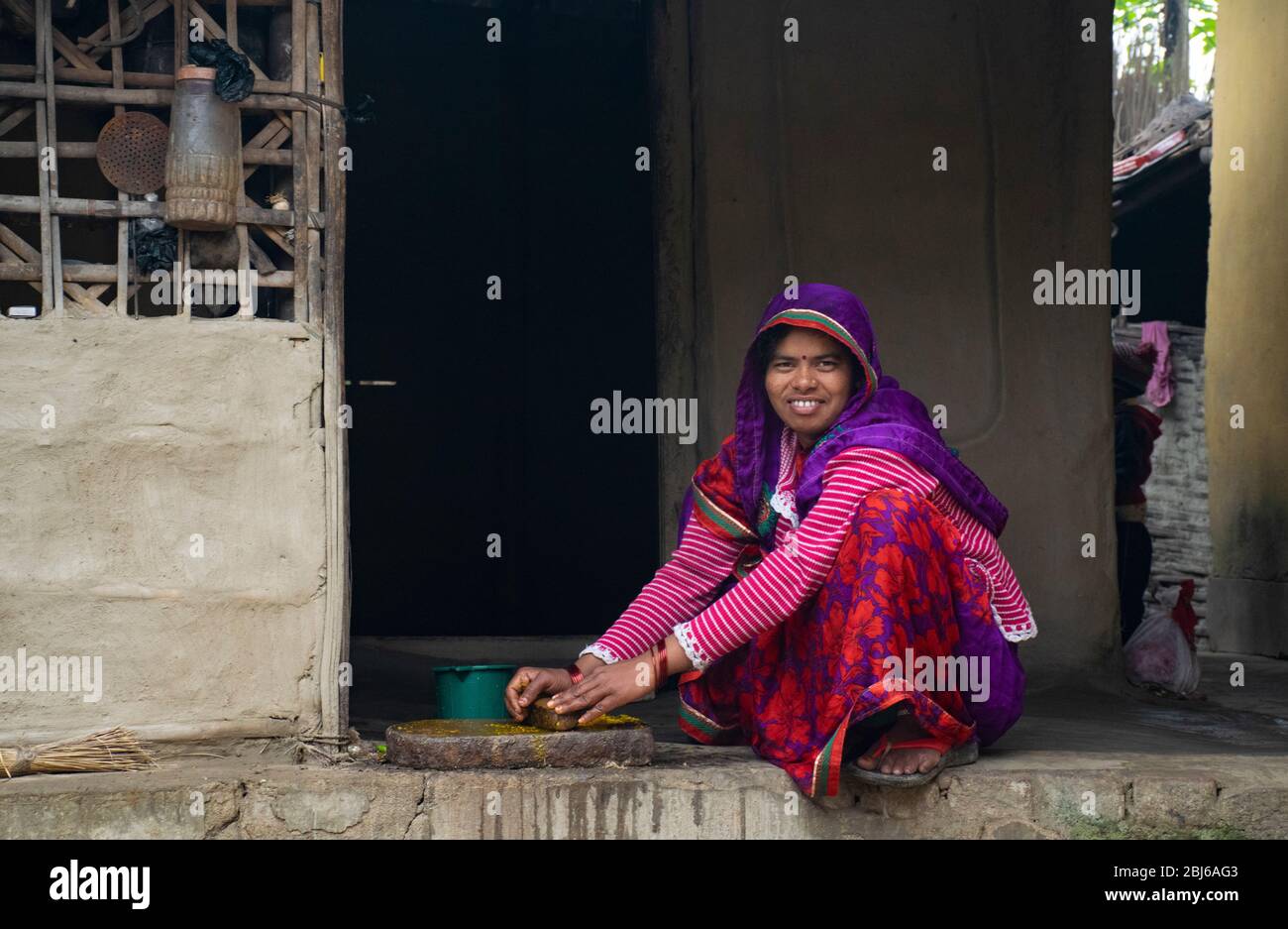 indian woman grinding spices for making food in kitchen Stock Photo