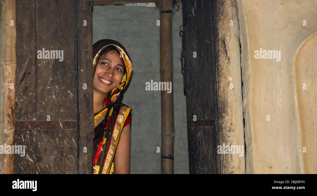happy woman standing at door of house in village, India Stock Photo