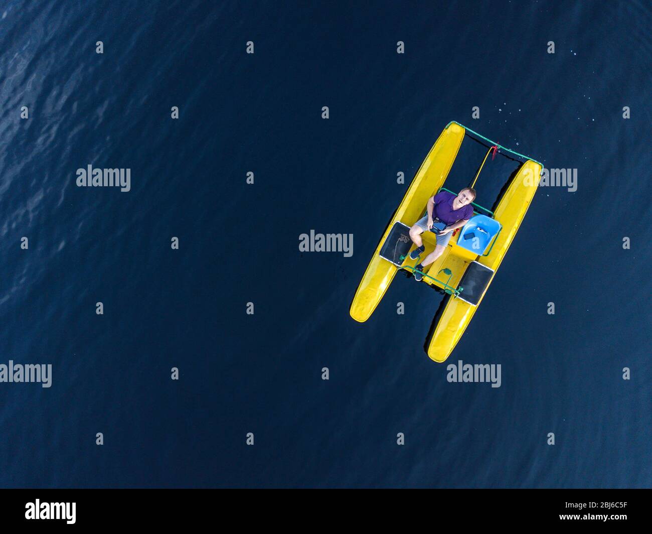 Aerial view of a man who swims on a lake on a pedal catamaran, a water