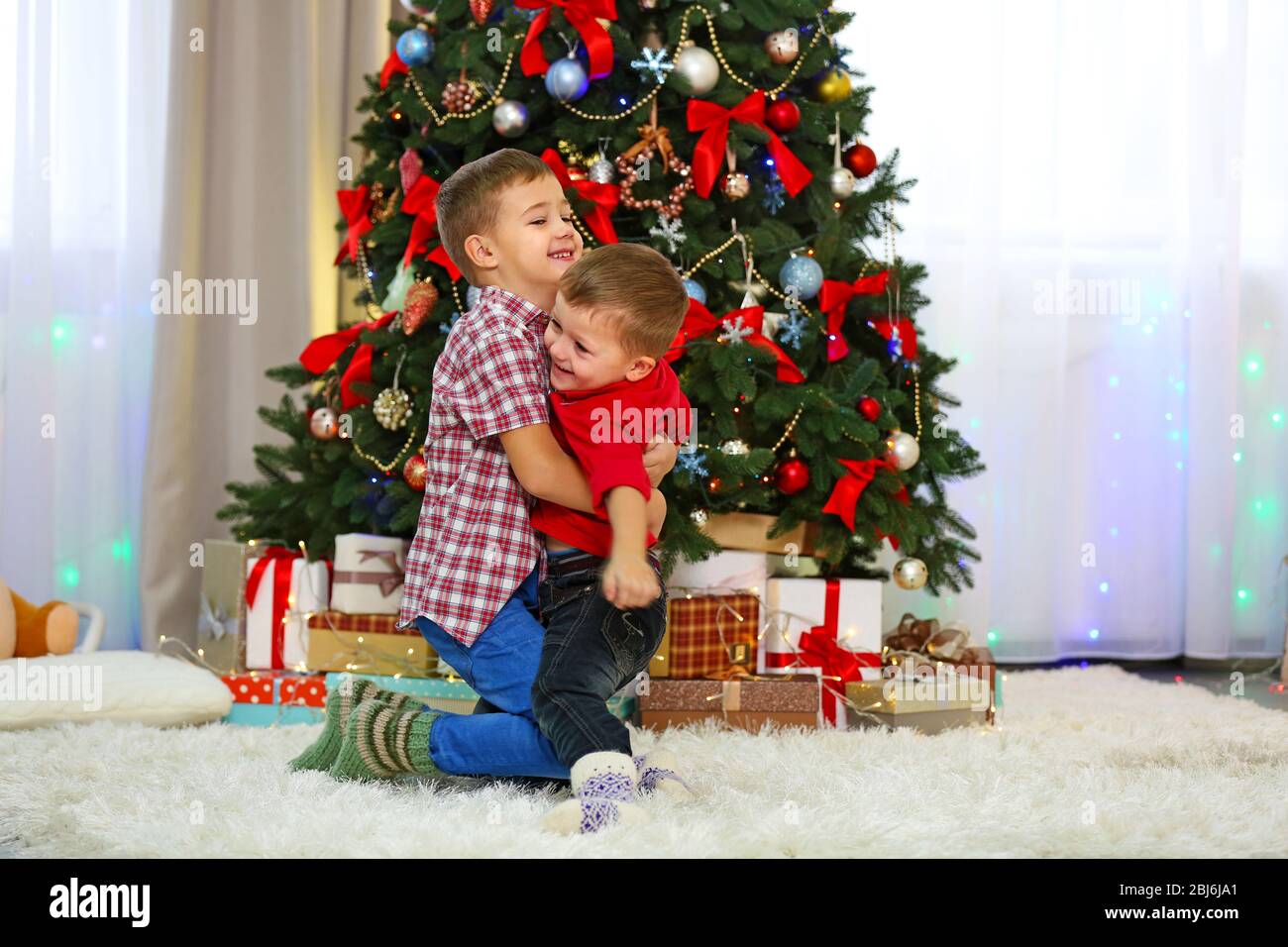 Two cute small brothers hugging on Christmas tree background Stock ...
