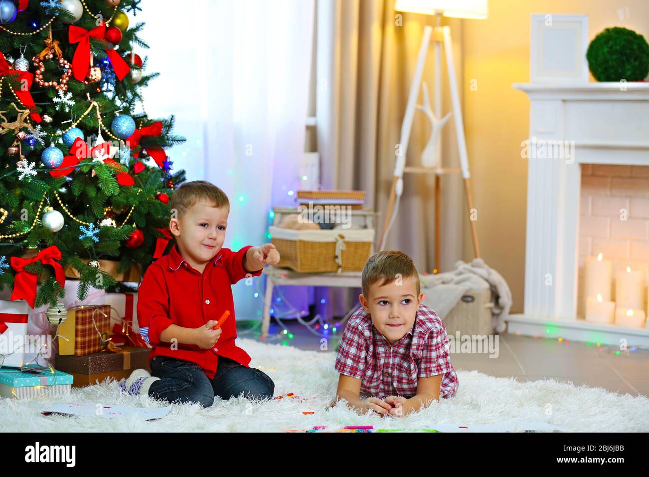Two cute small brothers playing on Christmas tree background Stock ...
