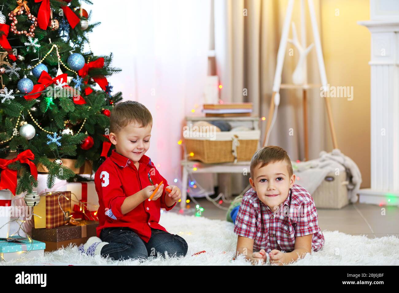Two cute small brothers playing on Christmas tree background Stock ...