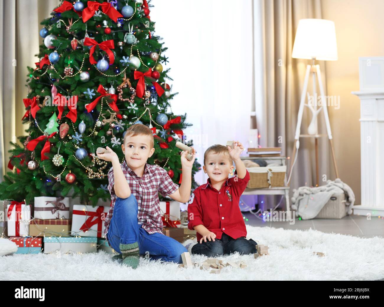 Two cute small brothers playing with wooden toys on Christmas tree ...