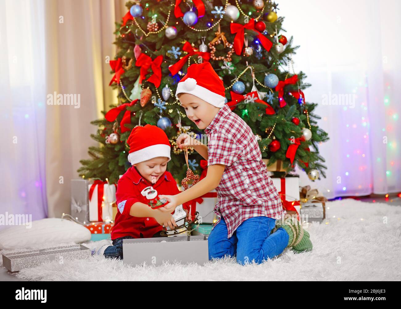 Two cute small brothers opening gifts on Christmas decoration ...