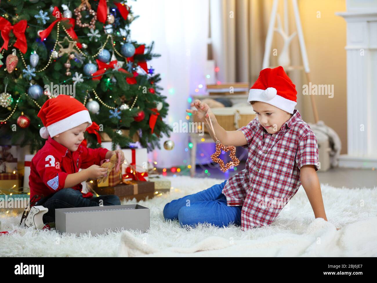 Two cute small brothers opening gifts on Christmas decoration ...