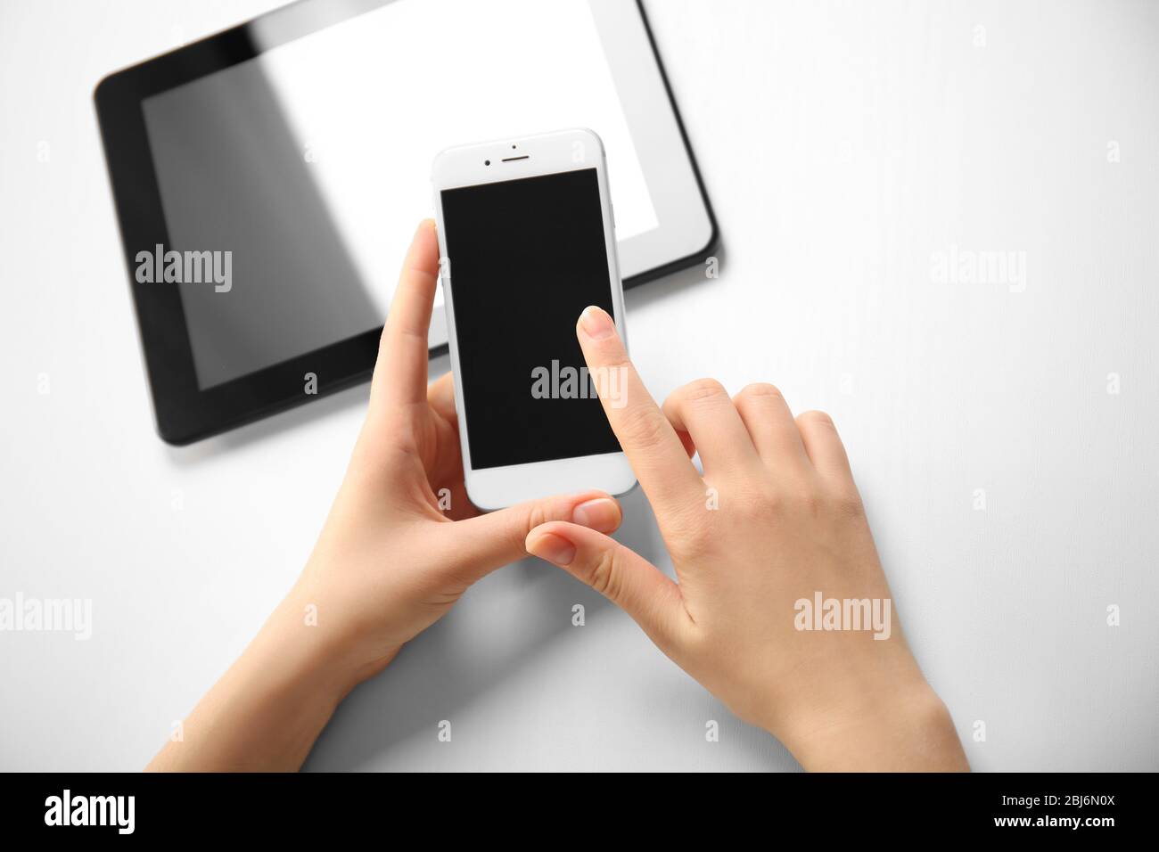 A tablet and female hands using mobile phone, isolated on white Stock ...