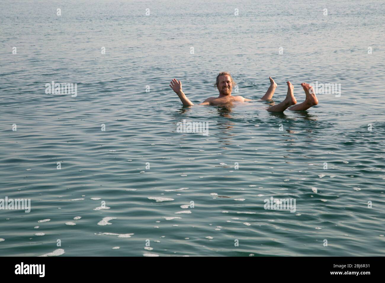 Happy smiling man floating on his back in the Dead Sea Stock Photo