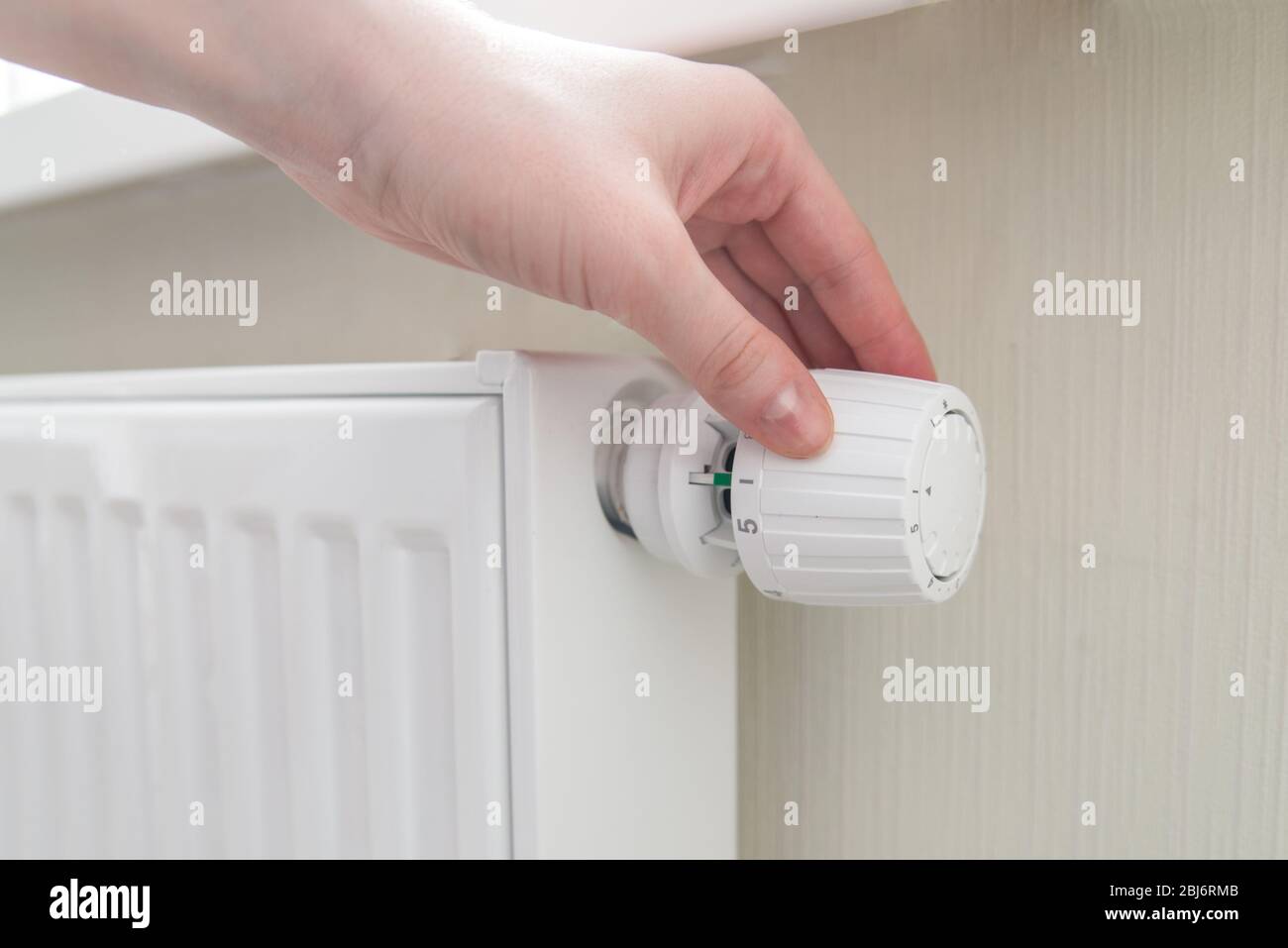 Home central heating system. Woman's hand turns the regulator. House energy efficiency Stock Photo