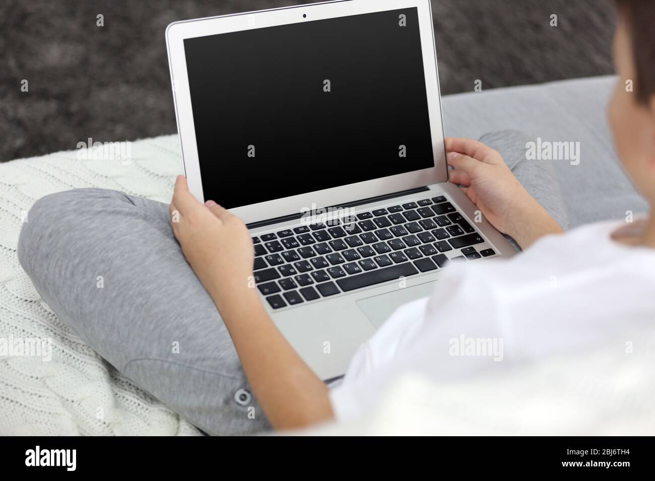 Little boy using laptop on a sofa at home, close up Stock Photo - Alamy