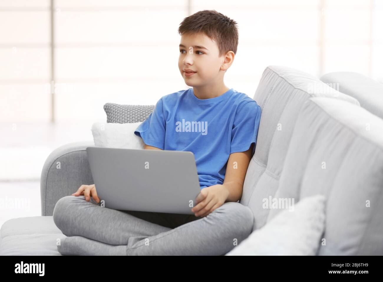 Little boy using laptop on a sofa at home Stock Photo - Alamy