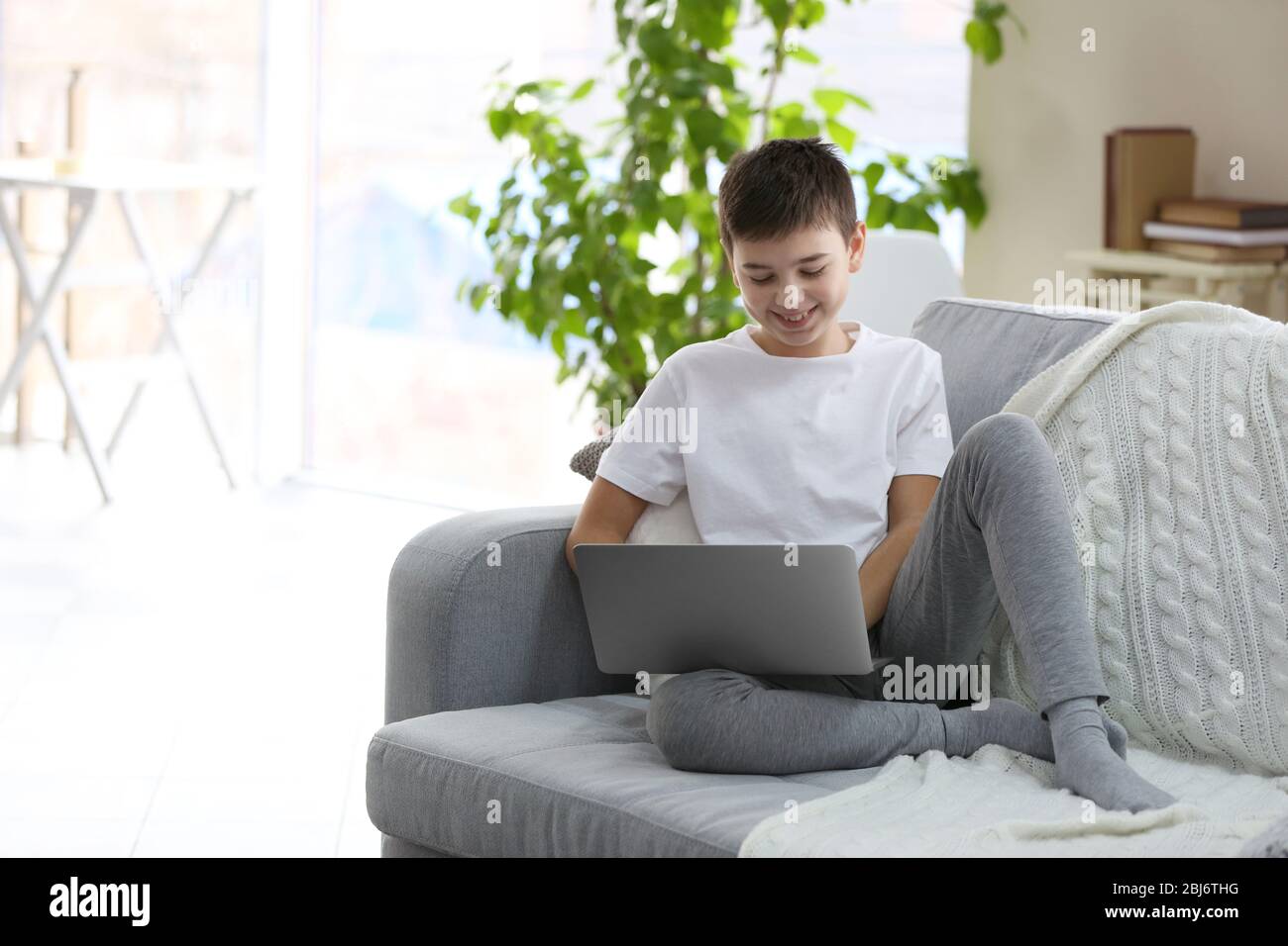 Little boy using laptop on a sofa at home Stock Photo - Alamy