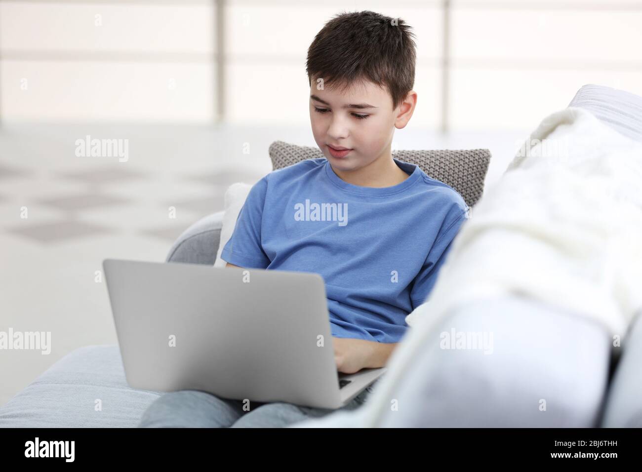 Little boy using laptop on a sofa at home Stock Photo - Alamy