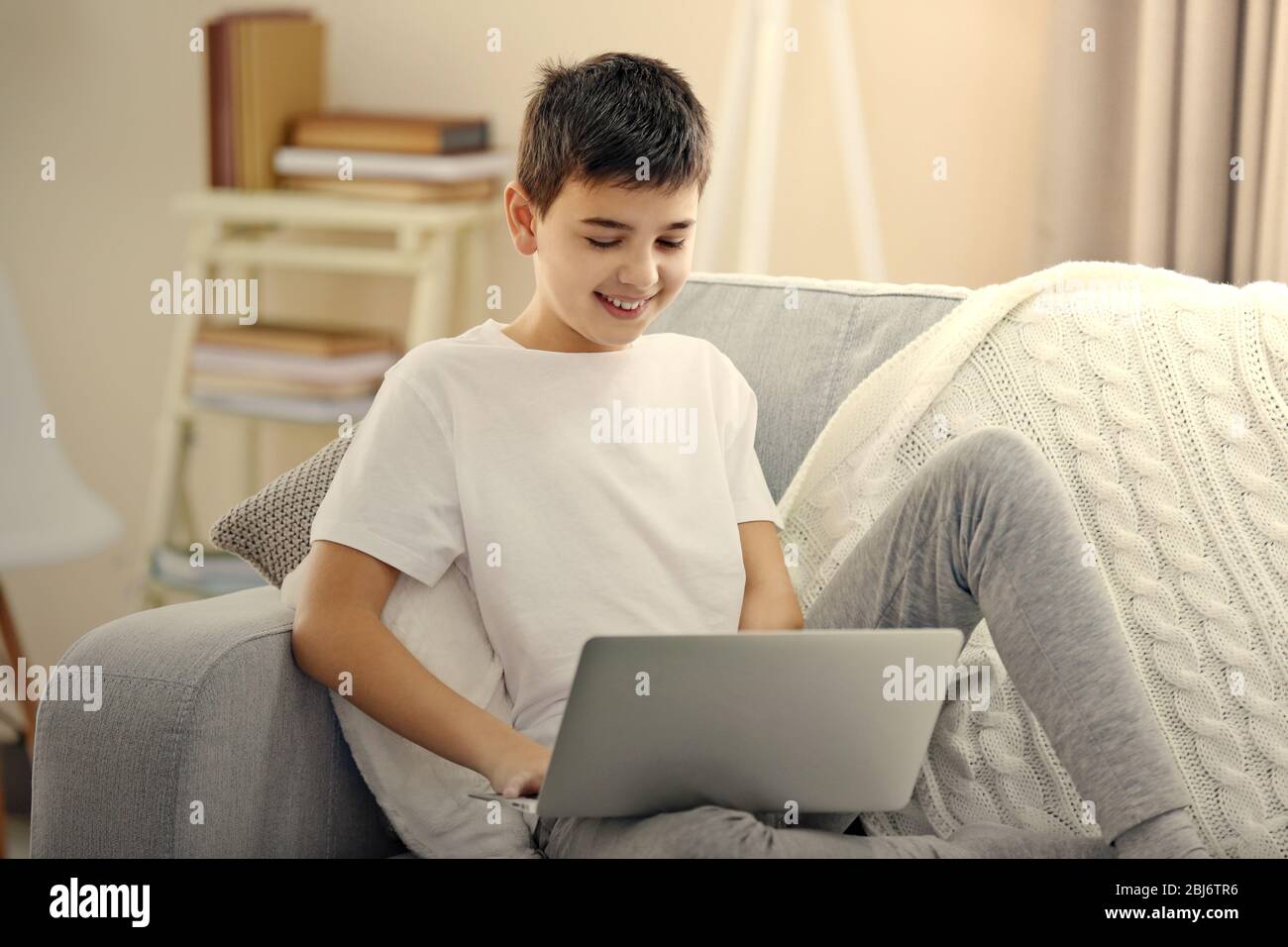 Boy using laptop on a sofa at home Stock Photo - Alamy