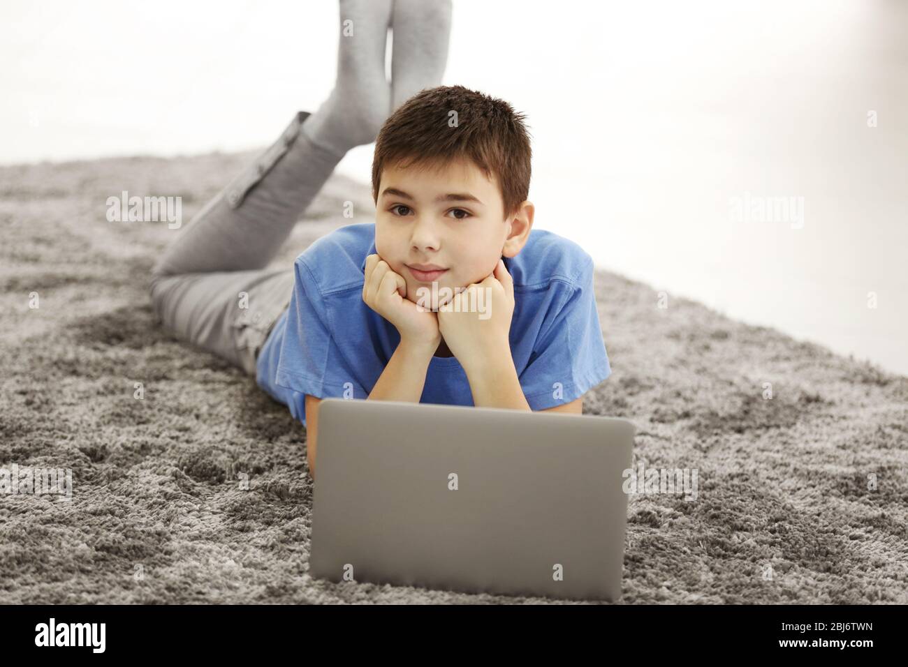 Boy with mobile phone and laptop lying on a floor at home Stock Photo ...